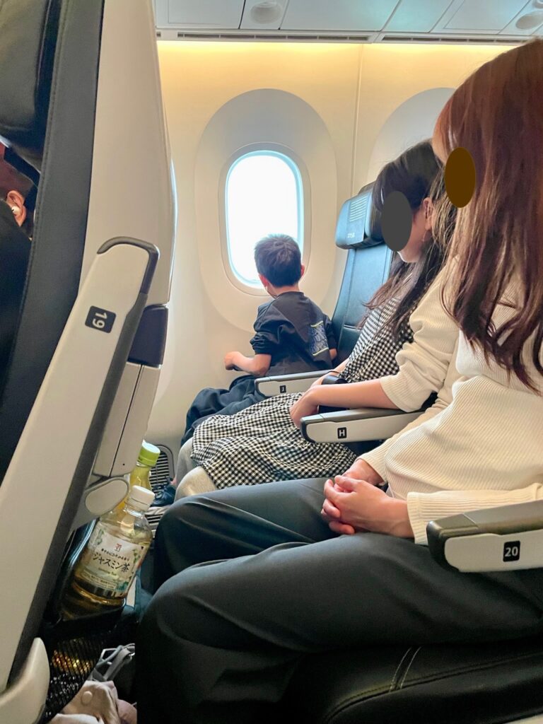 アメリカへ向かう飛行機の機内で座席に座る家族