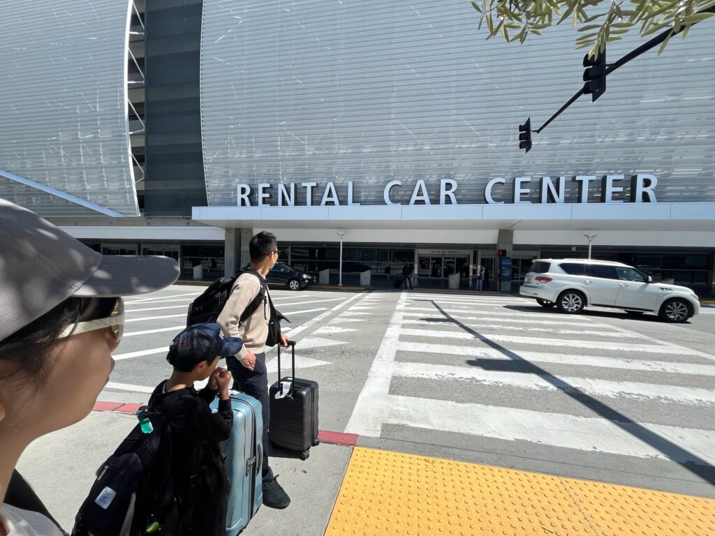サンノゼ空港のレンタカーセンター前で車を借りに向かう家族
