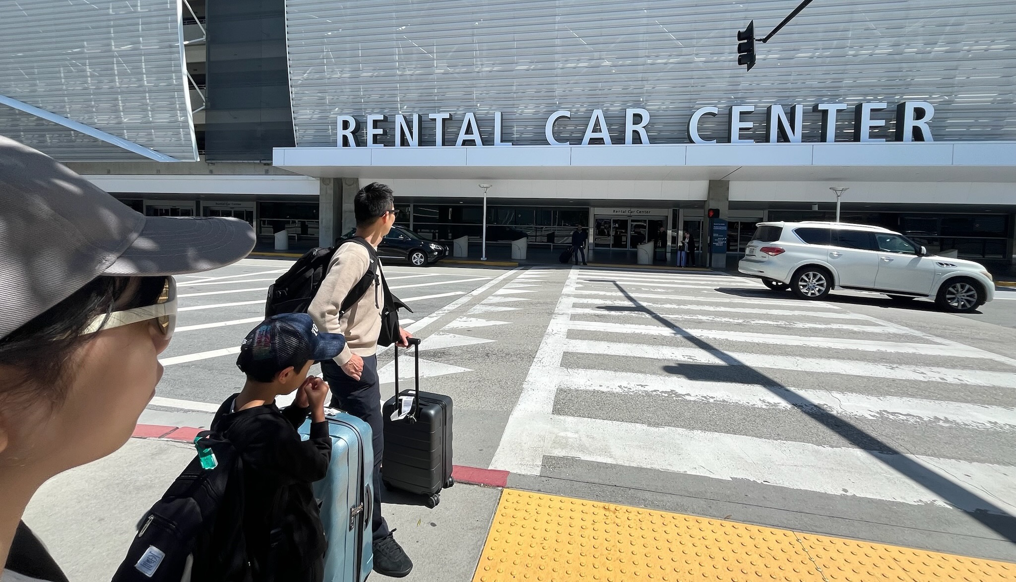 サンノゼ空港のレンタカーセンター前で車を借りに向かう家族